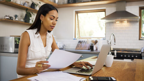 Eine Frau sitzt an ihrem Laptop und arbeitet.
