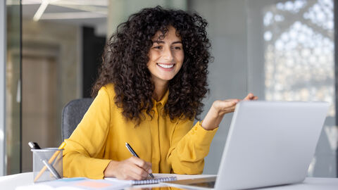 Frau sitz am Laptop und lächelt